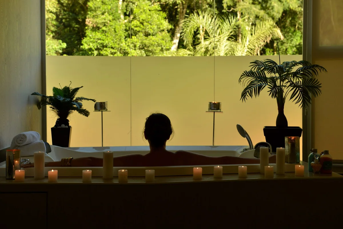 Banheira de hidromassagem do Spa Guavirá à luz de velas, com vista para a mata